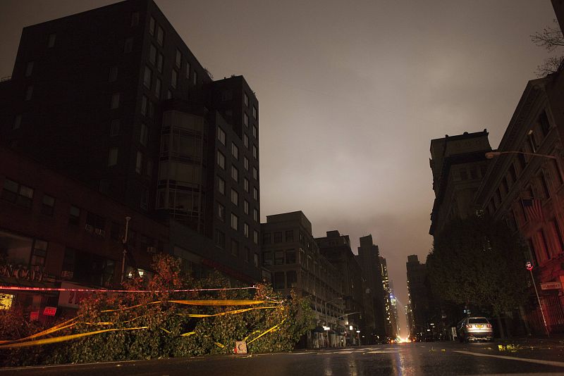 A fallen tree lays along a darkened Sixth Avenue in Chelsea during a blackout believed to be caused by rising river waters as Hurricane Sandy made its approach in New York