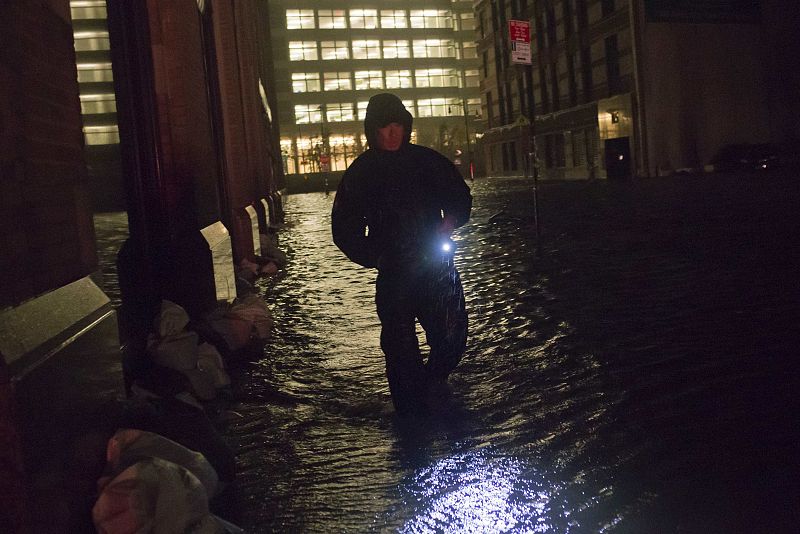 A security guard walks through a flooded street in the financial district of Manhattan