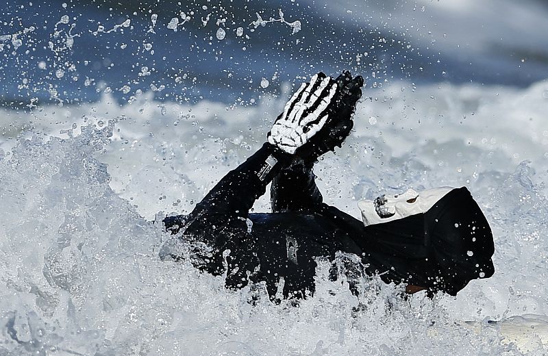 Un surfero surcando las olas de Santa Mónica disfrazado de esqueleto