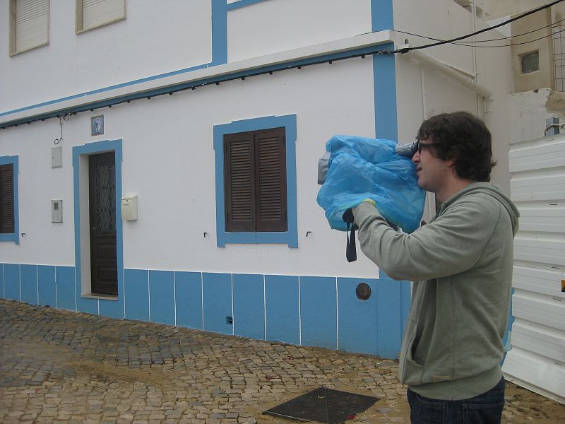 Grabando el pueblecito de Cacela Velha bajo la lluvia con un improvisado impermeable sobre la cámara