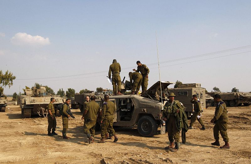 Israeli soldiers stand atop an armoured personnel carrier before a patrol along the border with the northern Gaza Strip