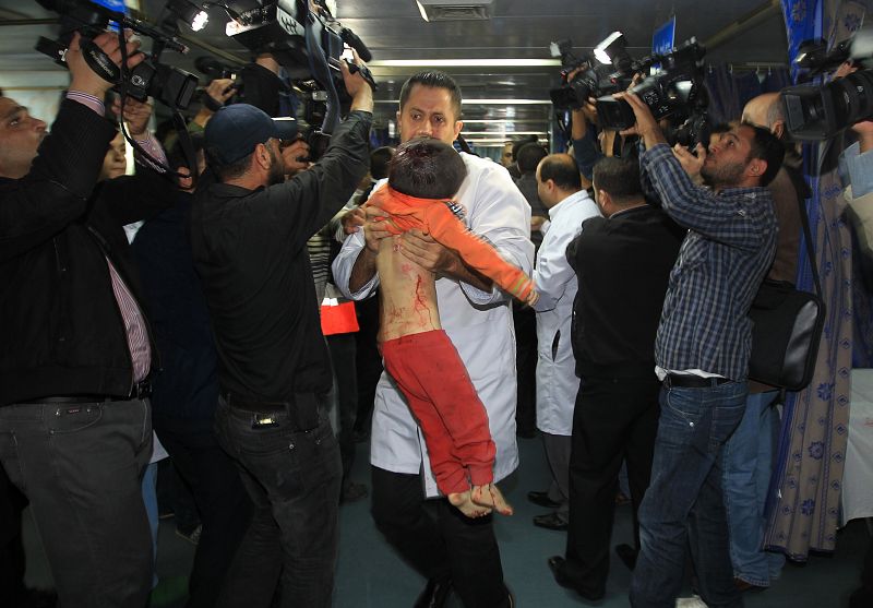 Un doctor palestino lleva en brazos el cuerpo de un niño asesinado por un ataque aéreo israelí en Gaza durante la visita de Haniye y Qandil al hospital al Shifa.