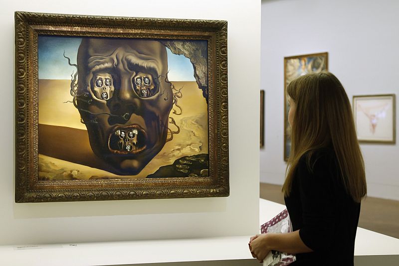A visitor looks at paintings by Spanish artist Salvador Dali during the press visit of the exhibition "Dali" at the Centre Pompidou modern art museum in Paris