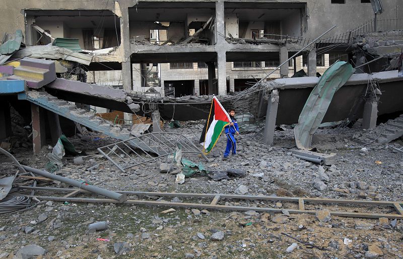Un chico palestino con la bandera nacional entre los restos del Estadio Deportivo de la ciudad de Gaza