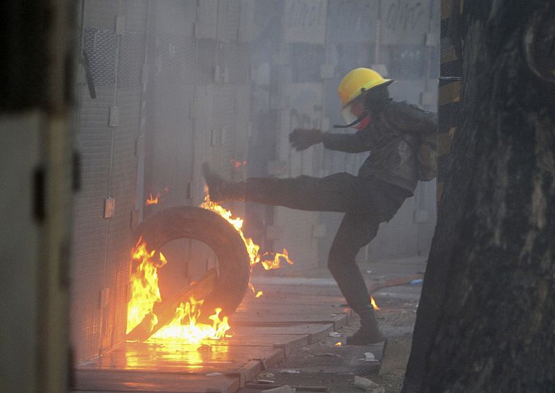 A protester kicks a burning tyre against a barricade set up around congress during a protest against Mexico's new President Pena Nieto, in Mexico City