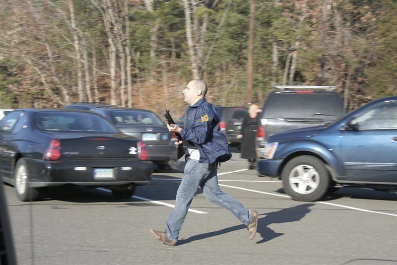 Fotografía cedida que muestra a un agente de policía corriendo con un arma en la mano hacia la escuela Sandy Hook en Newtown.