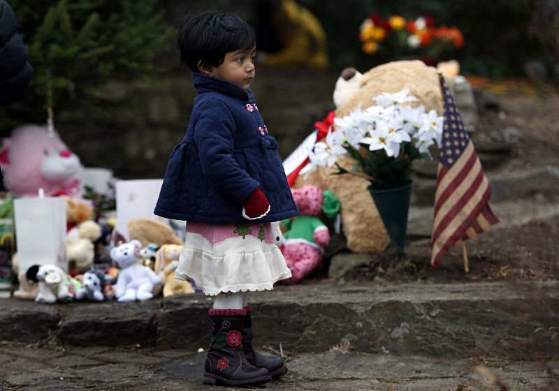 Girl stands near a makeshift memorial near the Sandy Hook Elementary School for the victims of a school shooting in Newtown, Connecticut