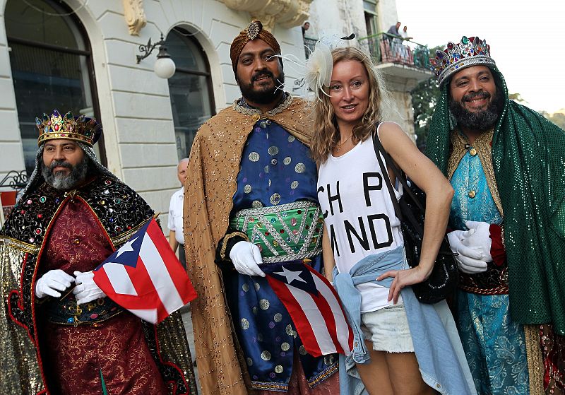 Una turista posa con hombres disfrazados de Reyes Magos durante una ceremonia para celebrar la epifanía en la Catedral de La Habana