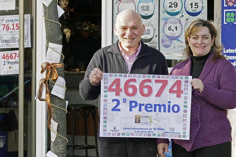 Los propietarios del bar "O Noso", despacho de Loterias y Apuestas del Estado en Becerreá (Lugo), posan junto al número agraciado con el segundo premio.