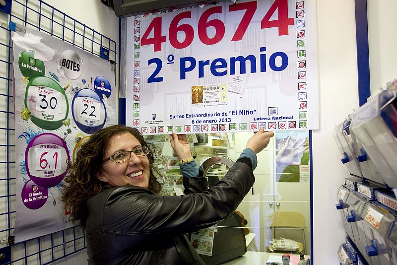 La lotera Ana Balbontin sostiene un cartel del número agraciado con el segundo premio.