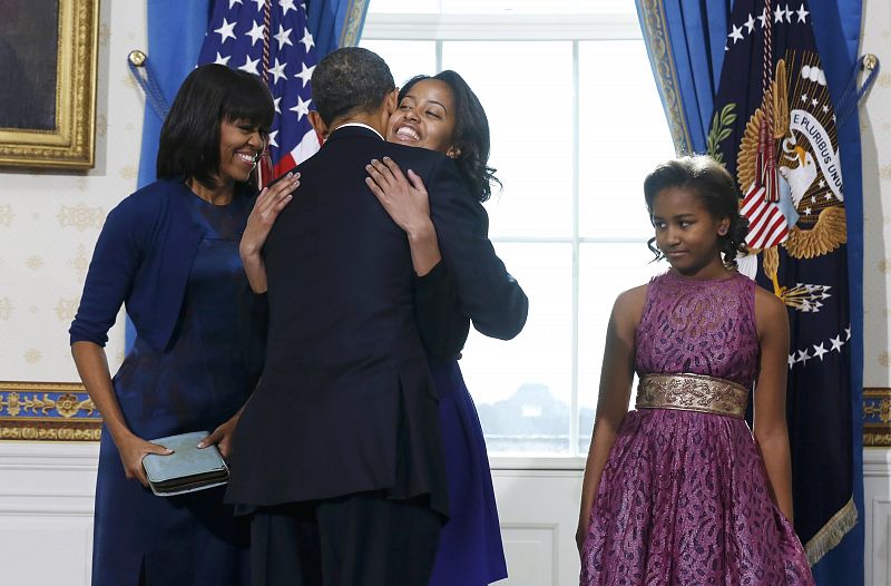 U.S President Barack Obama gets a hug from his daughter Malia as wife Michelle and daughter Sasha looks on in the Blue Room of the White House in Washington