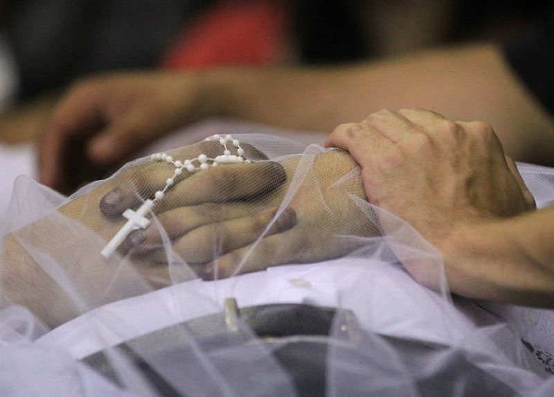 Un familiar toma la mano de un muerto  en el incendio de una discoteca en Brasil. 