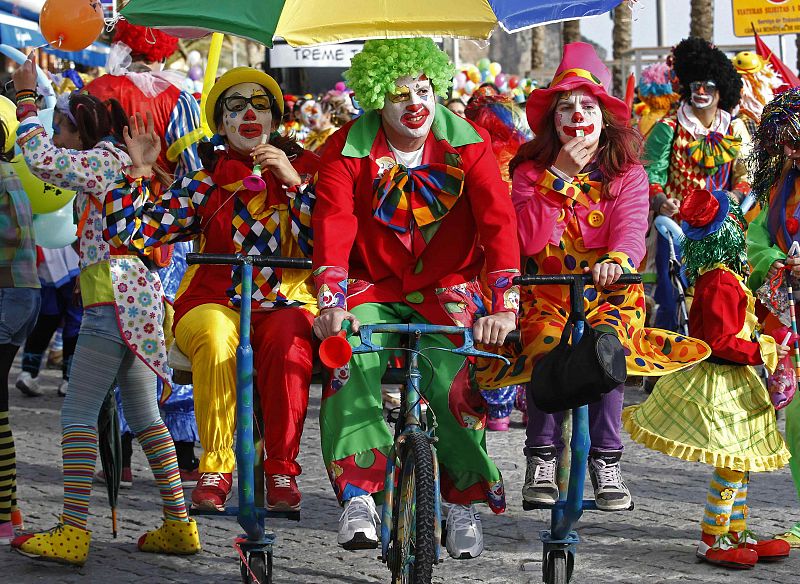 Carnival revellers dressed as clowns pedal on the clowns parade in Sesimbra village