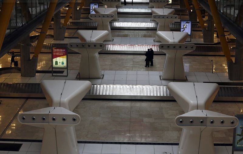 Dos pasajeros en la zona de recogida de equipajes de la T4 de Barajas