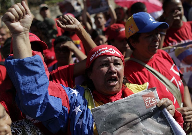 Una mujer llora la muerte de Chávez ataviada con los colores de la bandera venezolana y una foto del comandante