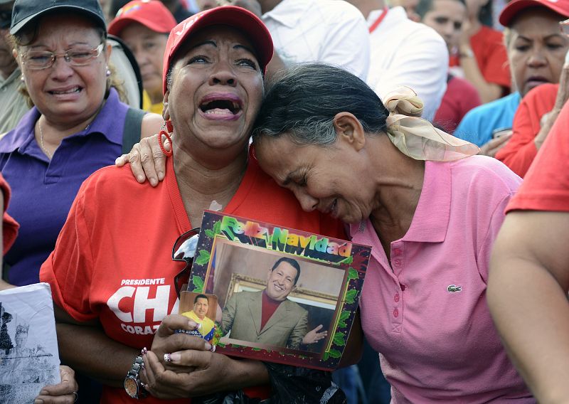 Varias mujeres lloran la muerte del difunto presidente venezolano Hugo Chávez