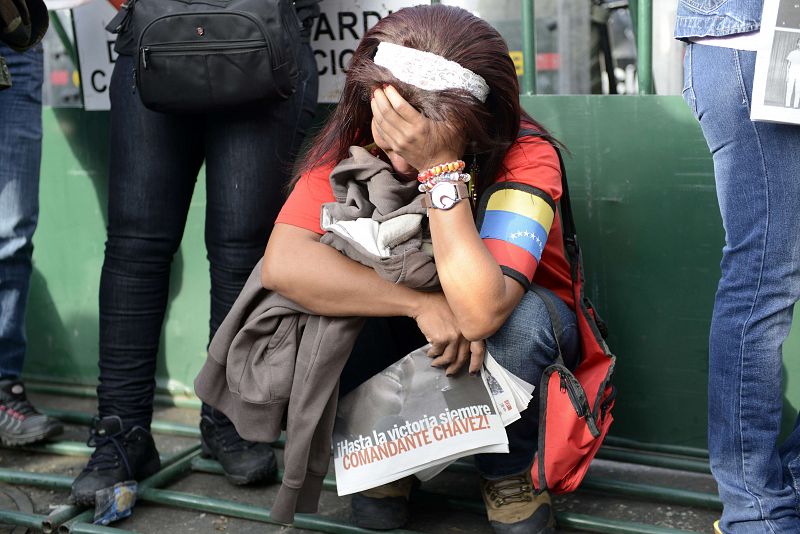 Una venezolana desolada sostiene un periódico en el que se lee "Hasta la victoria siempre, comandante Chávez"