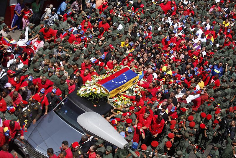 El coche fúnebre que traslada a Hugo Chávez, custodiado por militares y rodeado por cientos de simpatizantes.