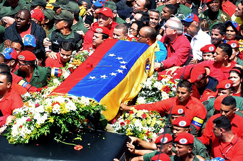 Ciudadanos y fuerzas de seguridad rodean el coche fúnebre del presidente Chávez, cuyo ataúd está cubierto por la bandera venezolana