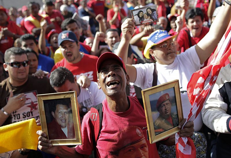 Un hombre llora la muerte de Chávez con dos fotos del difunto presidente de Venezuela