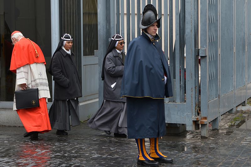 Uno de los cardenales llega al Vaticano, protegido por uno de los miembros de la guardia suiza