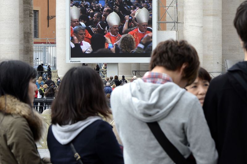 Un grupo de turistas observa una pantalla gigante que mostraba el interior de la misa "pro eligendo papa"