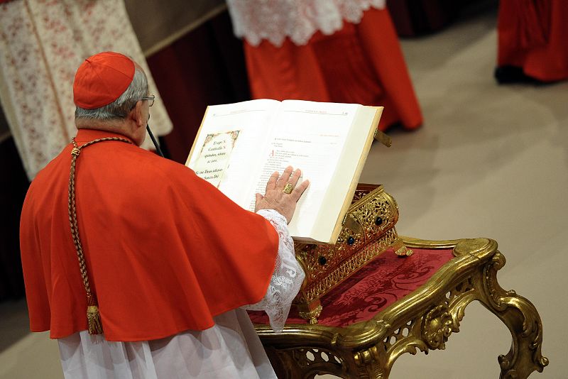 Uno de los cardenales que componen el cónclave posa su mano sobre la Biblia realizando el juramento