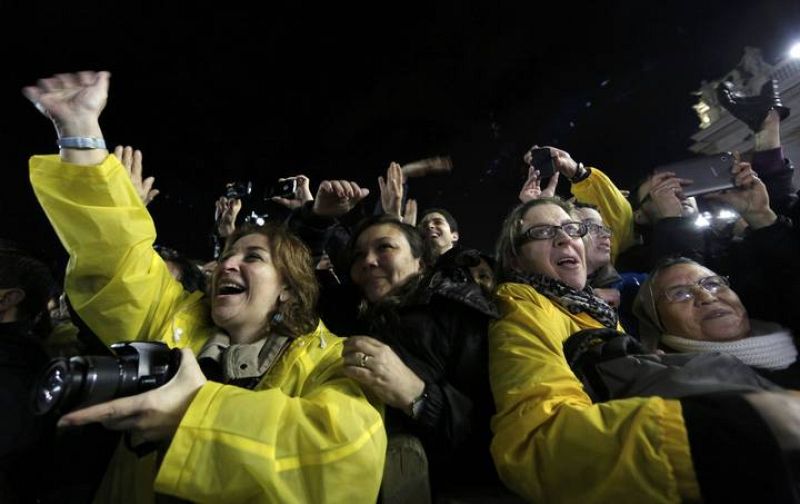 Los feligreses que han acudido en masa a la plaza de San Pedro saludan al nuevo papa Francisco, asomado al balcón de la Basílica