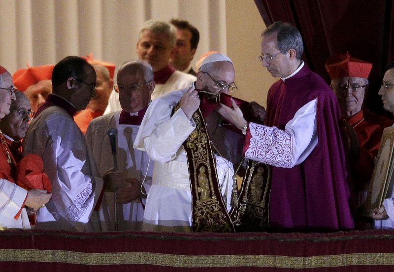 El recientemente nombrado papa Francisco besa el pectoral de obispo segundos antes de que le fuera impuesto