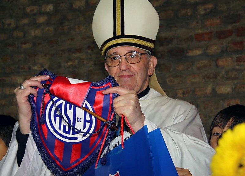 Como gran aficionado que es al club de fútbol San Lorenzo de Almagro sostiene un banderín del equipo