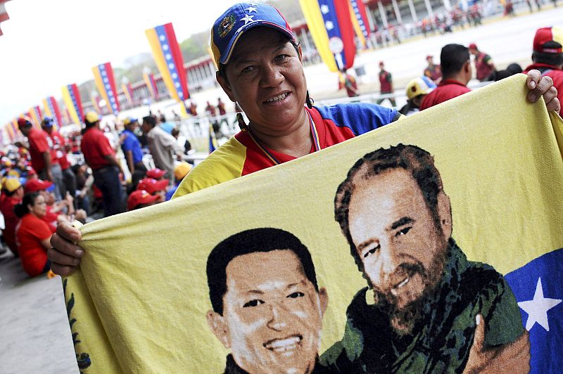 Un ciudadano sostiene una bandera de venezuela con la imagen de Chávez y Castro durante el traslado del féretro de Hugo Chávez al Cuartel de la Montaña