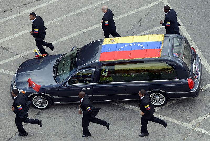 Los escoltas corren alrededor del coche fúnebre que transporta el cadáver de Hugo Chávez hacia el Cuartel de la Montaña