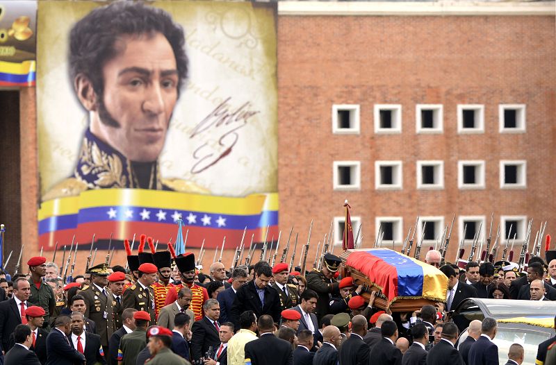 El féretro de Húgo Chávez es transportado por miembros del ejército con la imagen de Simón Bolívar de fondo