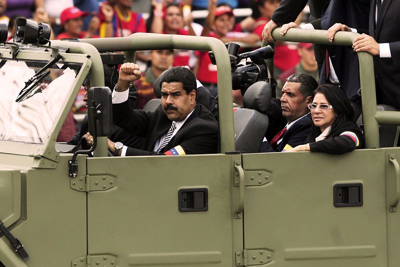 El presidente encargado de Venezuela, Nicolás Maduro, saluda con el puño en alto a los chavistas que acompañan al coche fúnebre en su recorrido hasta el Cuartel de la Montaña
