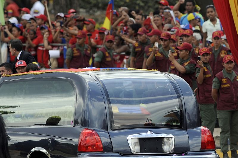 Incluso los miembros del cuerpo de seguridad se giran para fotografiar al coche que traslada el féretro del difunto presidente de Venezuela, Hugo Chávez