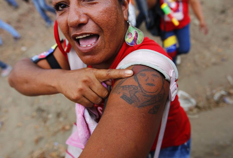 Una mujer chavista muestra su tatuaje con el rostro del fallecido presidente de Venezuela, cuyo féretro descansa provisionalmente en el Cuartel del Monte, donde comenzó su fallido golpe de Estado