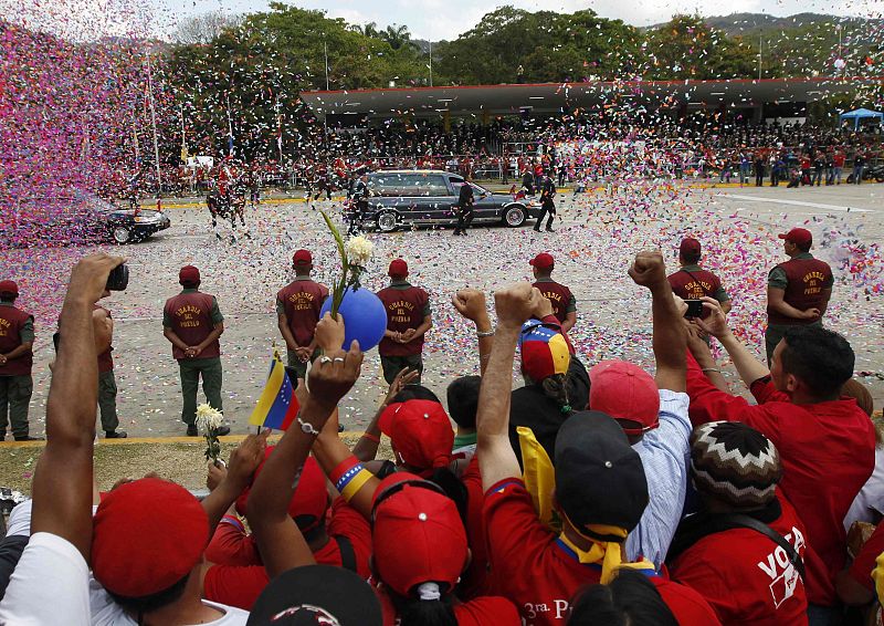 People react as the hearse carrying the body of Venezuela's late President Hugo Chavez drives past during his funeral parade in Caracas