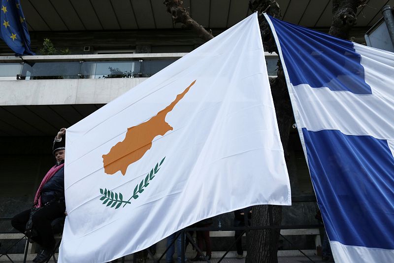 Un manifestante sostiene unidas las banderas de Chipre y Grecia durante las manifestaciones contra el rescate financiero