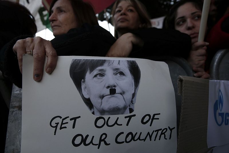 Una pancarta representa a la canciller alemana Angela Merkel caracterizada como Adolf Hitler, junto al lema "sal de nuestro país", en protesta por la propuesta de rescate financiero a Chipre