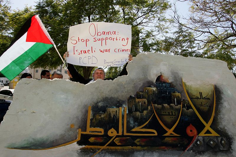 Un palestino sostiene un cartel en el que exige a Obama que deje de apoyar los crímenes de guerra de Israel