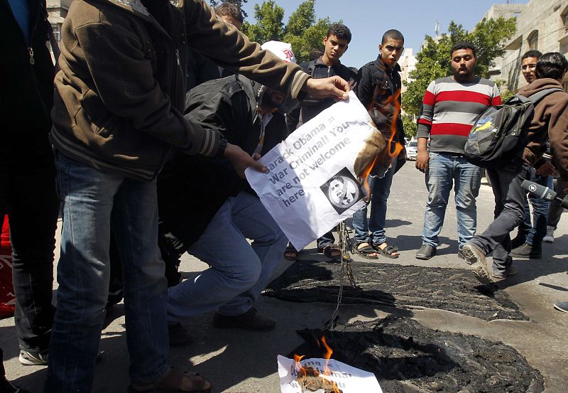 Manifestantes palestinos prenden fuego a unos carteles en los que se lee "Barack Obama, criminal de guerra, su visita no es bienvenida", durante las protestas por la primera visita oficial del presidente estadounidense a Israel