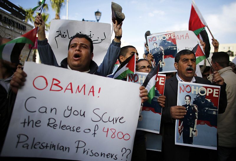 Palestinian demonstrators hold placards, some depicting U.S. President Obama dressed as an Israeli soldier during a protest in Ramallah