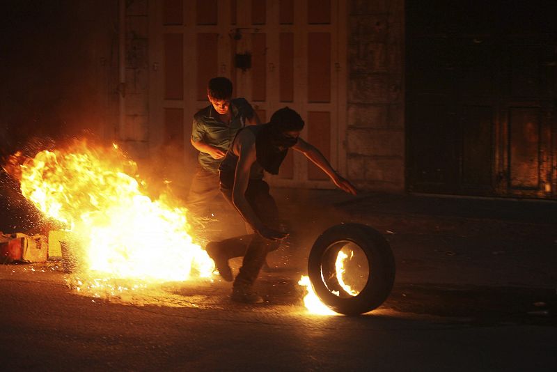 Menifestantes palestinos incendian neumáticos y encienden hogueras en las calles durante los enfrentamientos contra la policía de Cisjordania, con motivo de la visita del presidente Obama