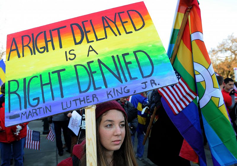 Una de las manifestantes pro-matrimonio homosexual a las puertas del Tribunal Supremo sostiene una pancarta con una cita de Martin Luther King en la que se lee: "Un derecho retrasado es un derecho negado"