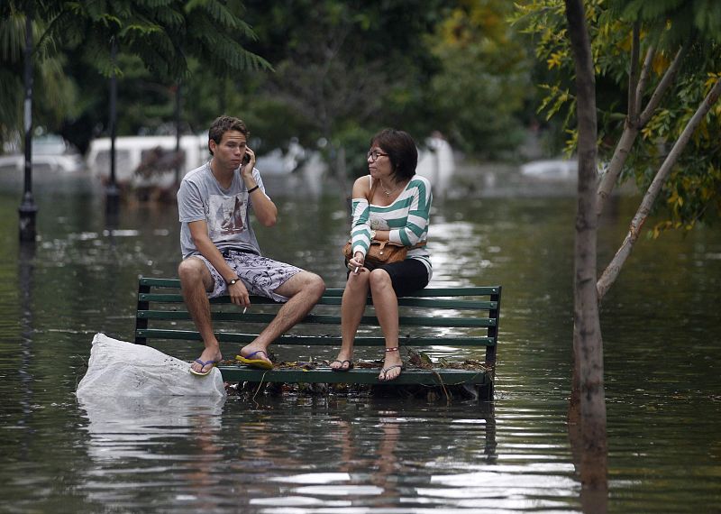 Dos ciudadanos conversan en un banco aislados por la inundación