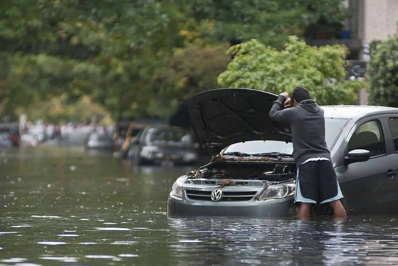 Un hombre examina su coche, arrastrado por la inundación