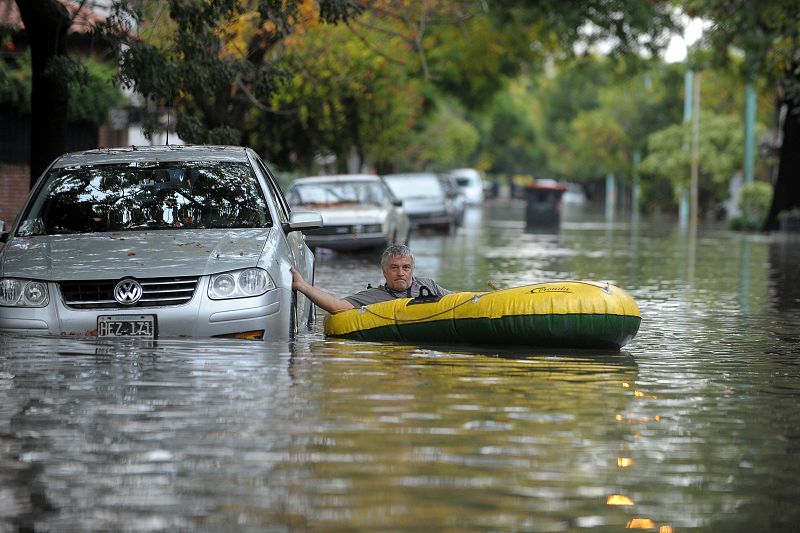 Un ciudadano se desplaza por la riada en una barca hinchable