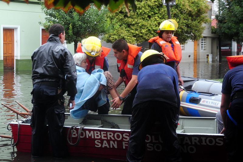 Los bomberos evacúan en barca a una anciana que había quedado aislada por el temporal en La Plata, Argentina