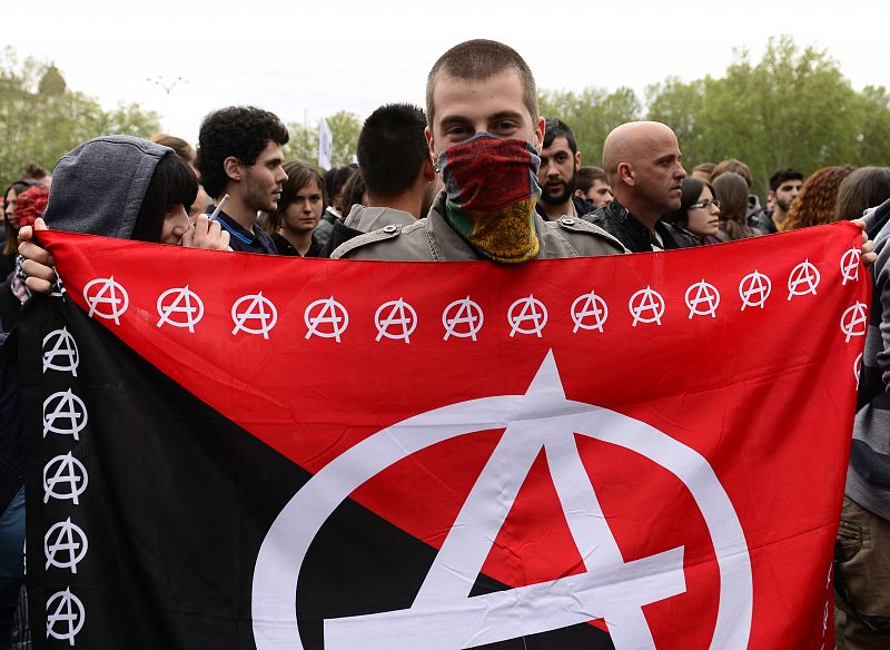 Un manifestante enseña una bandera anarquista