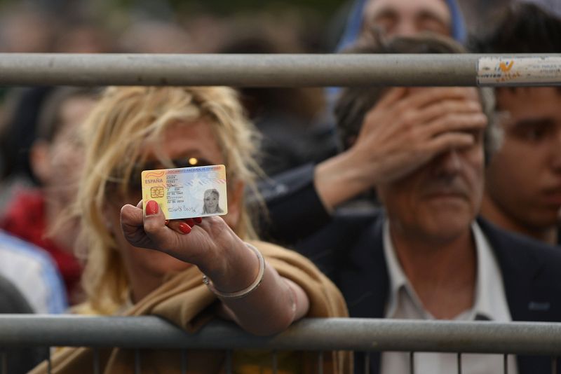 Una mujer enseña su DNI ante el Congreso de los Diputados